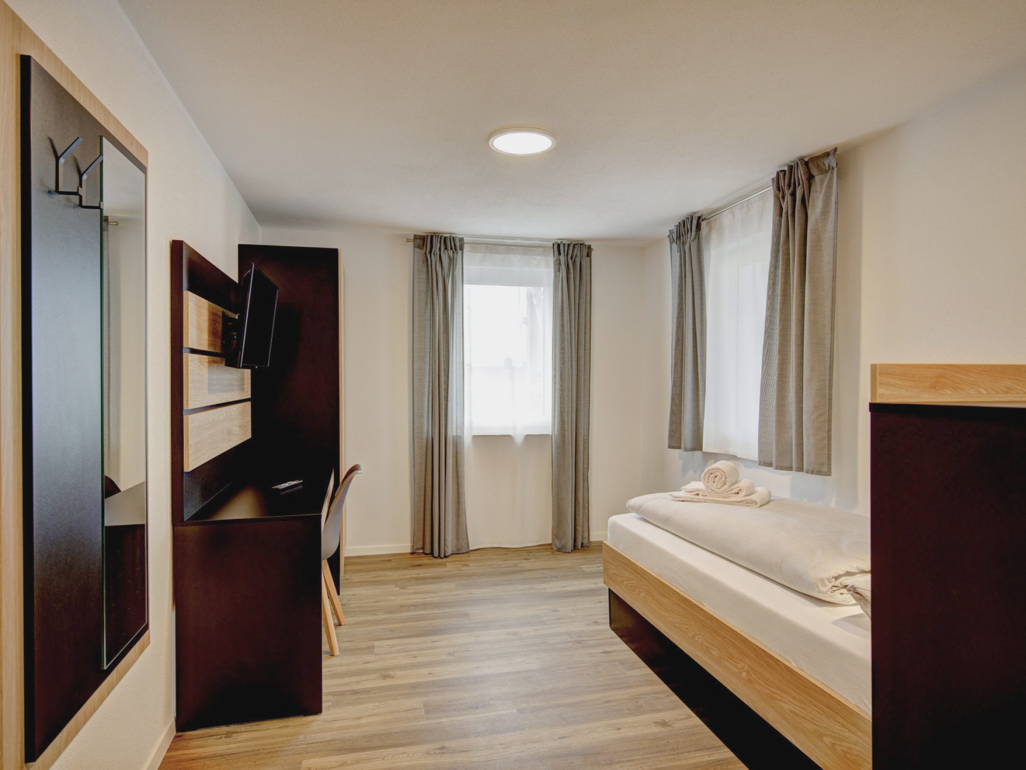 Schönes Apartmentzimmer mit Einzelbett, Arbeitsbereich, Schrank und Garderobe